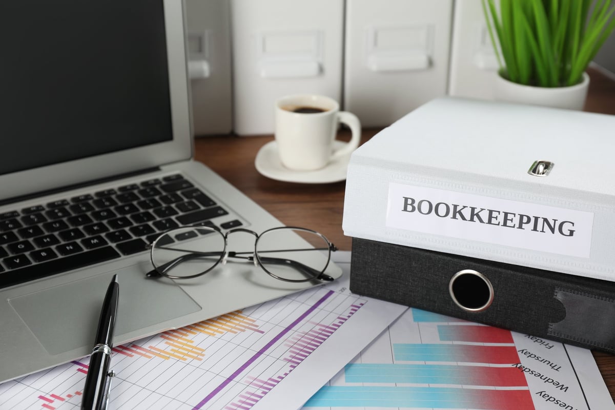 A bookkeeper's workplace with folders, laptop, and documents on a desk