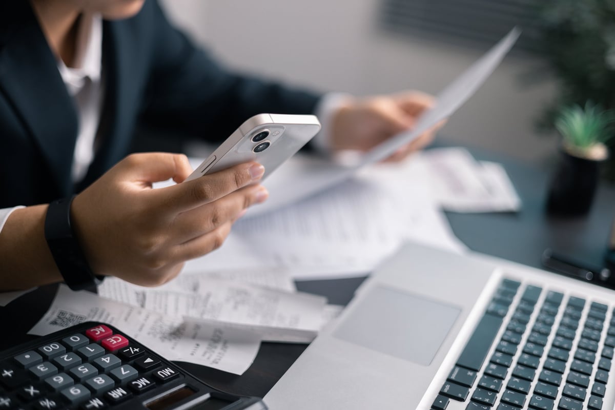 Businessman calculating financial figures with a calculator and charts at a desk